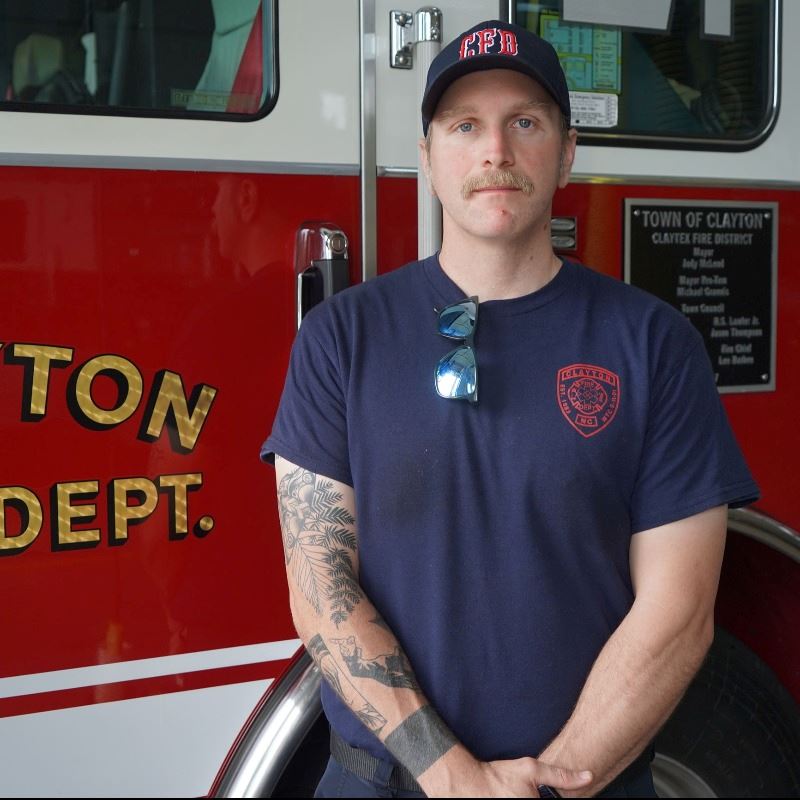 Dustin Adkins Stands in Front of Clayton Fire Truck