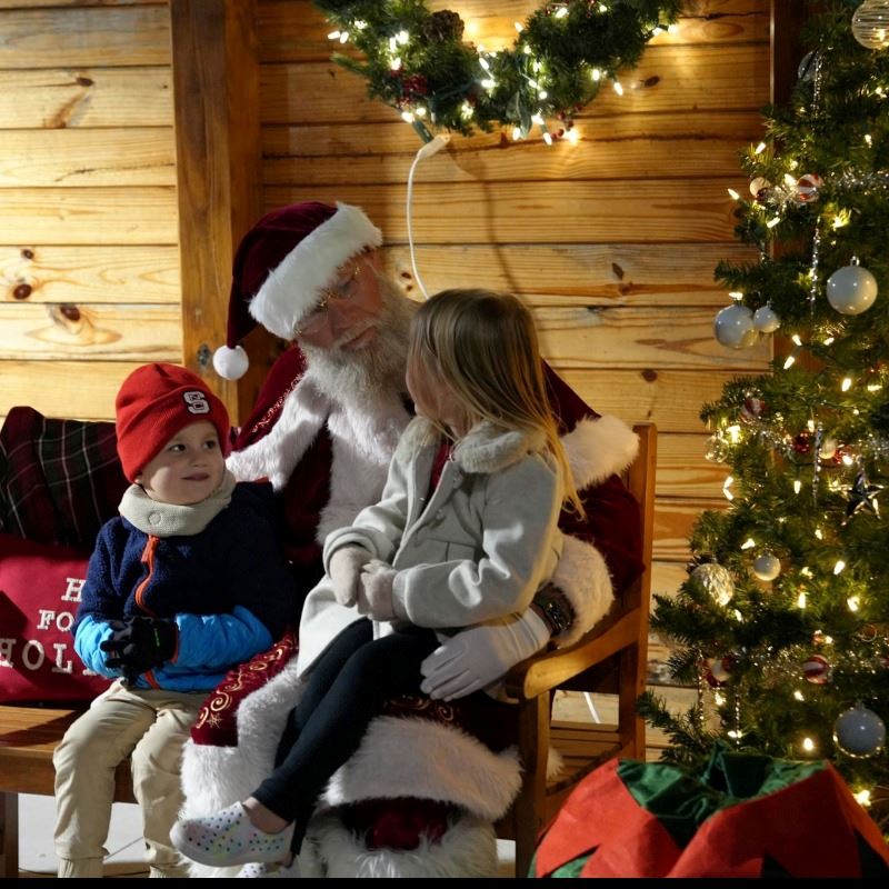 Two children sit with Santa during Merry Municipal Hot Cocoa