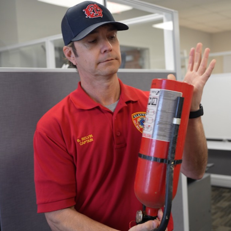 Captain Bryan Belvin gently shakes fire extinguisher to loosen inside contents