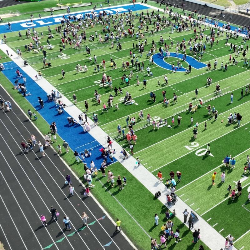Aerial view of Clayton High School football field with large crowd of children hunting easter eggs