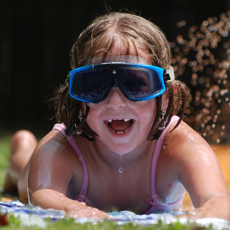 Girl on slip and slide with googles