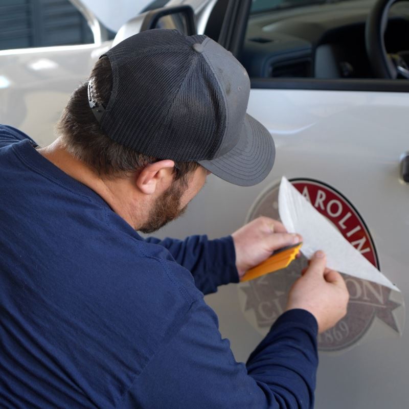 Town of Clayton mechanic applies town deal decal to the side of town vehicle