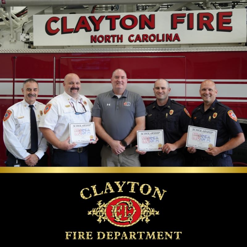3 clayton firefighters pose in front of firetruck with fire chief and scholarship presenter 