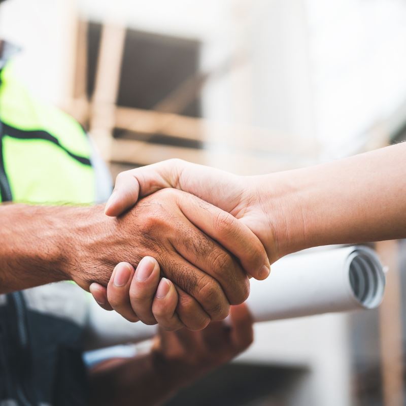 man in safety vest shakes another person's hand