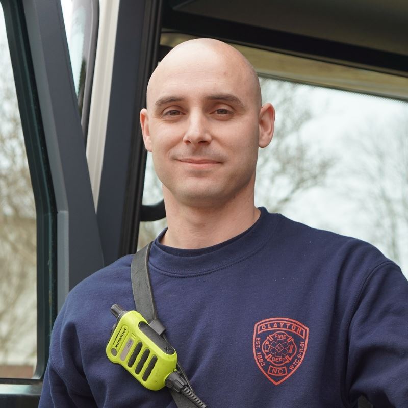 Nicholas Campasano poses at open driver side door of firetruck